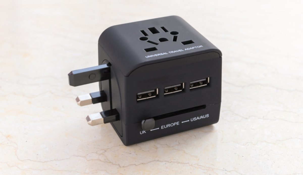 Universal travel adapter with USB ports on marble surface