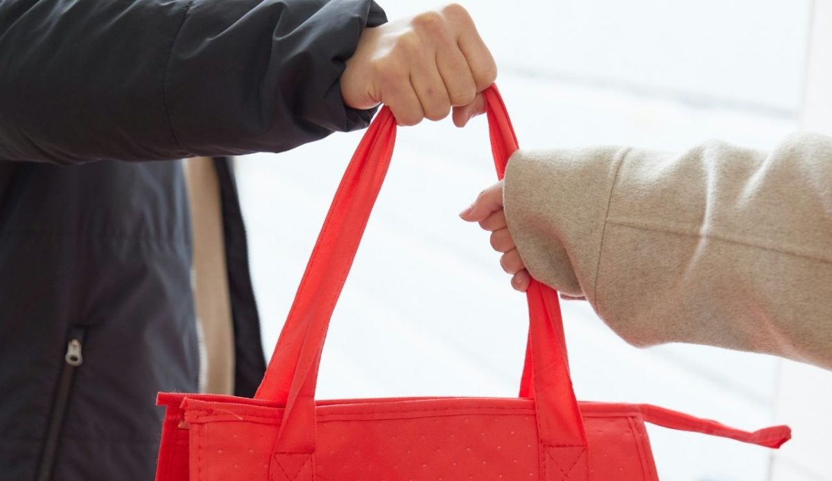 a person is giving hand bag to another person            