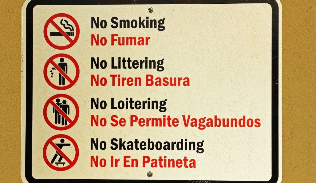 a sign board showing prohibited activities in english and spanish language                     