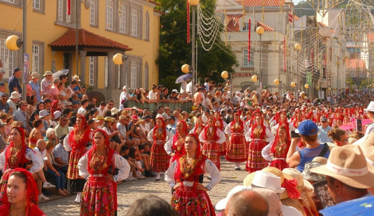 Folk dancers in traditional red costumes performing at a crowded festival in Portugal              