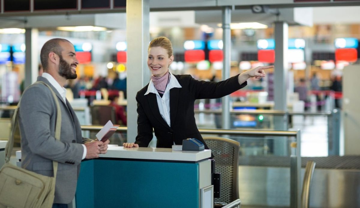 Airline check-in attendant showing direction to passenger at check-in counter 