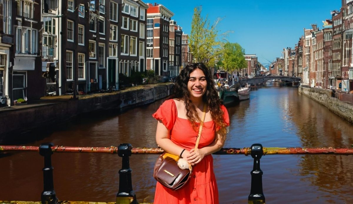 Young Smiling Woman Standing on a Bridge over the Canal in Amsterdam, the Netherlands       