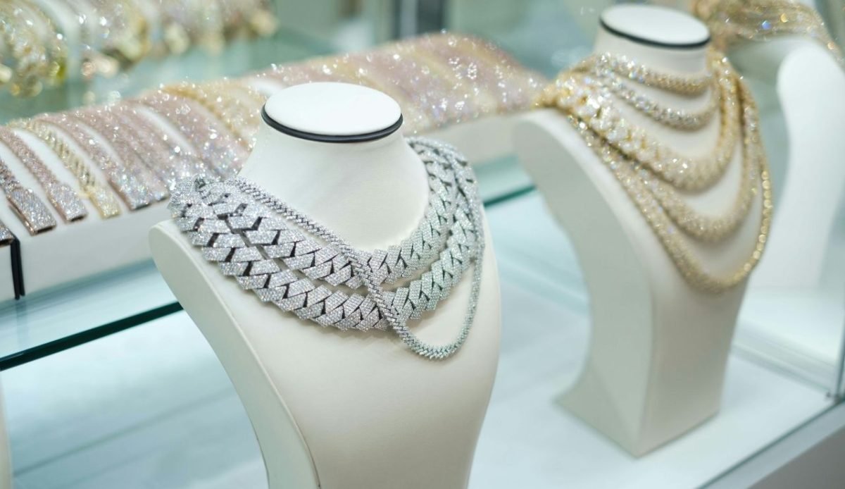 Diamond and gold necklaces displayed on white jewelry displays inside a glass showcase