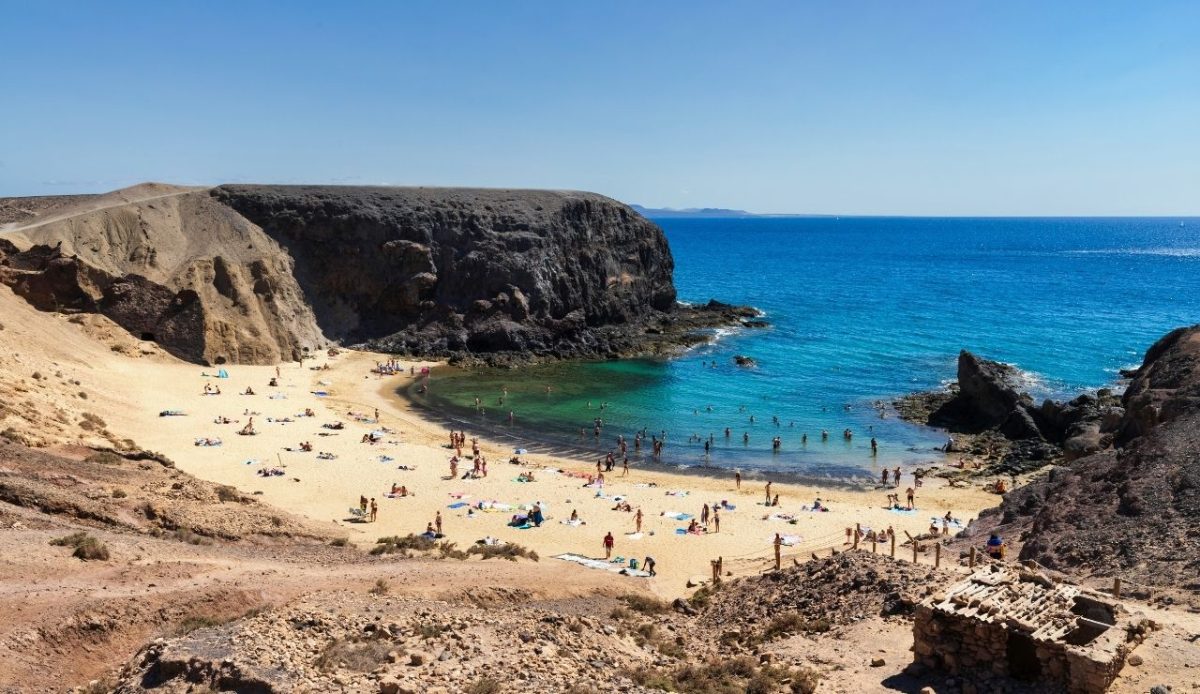 Golden sand beach at Playa de Papagayo with swimmers and sunbathers in Lanzarote, Spain                         