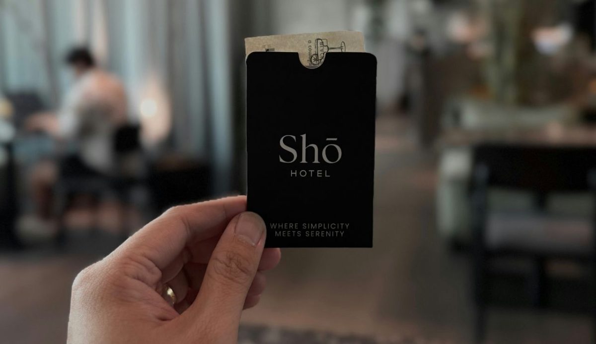 Hand holding a Shō Hotel key card in a modern lobby                     