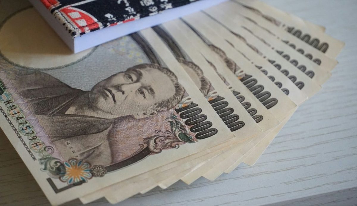 Japanese yen banknotes partially tucked into a fabric wallet on a table                            