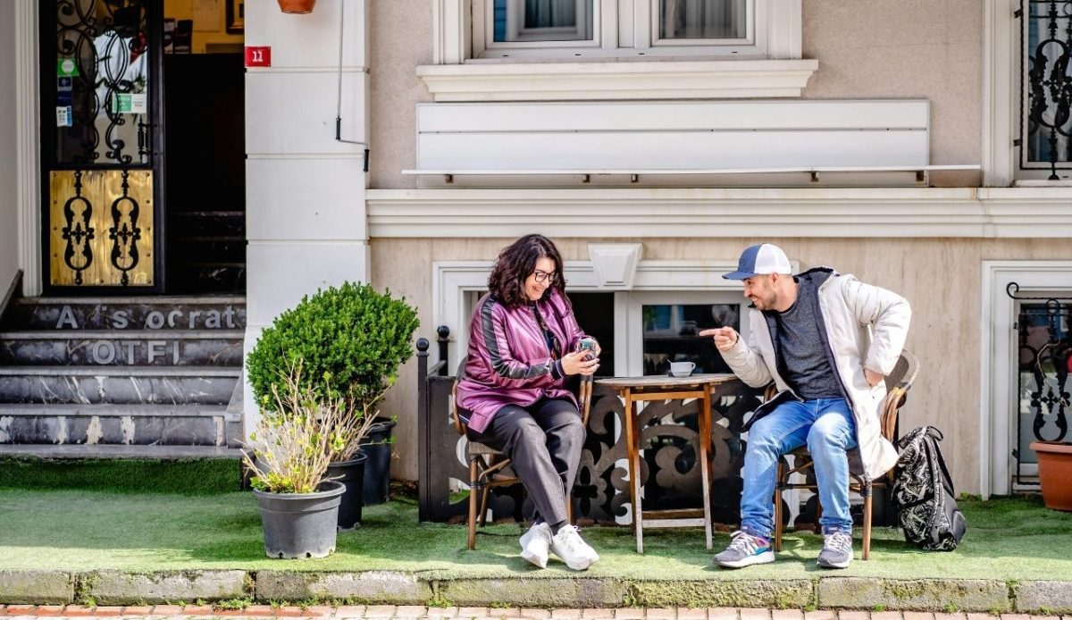 Man and Woman Sitting While Talking In Front of a House                        