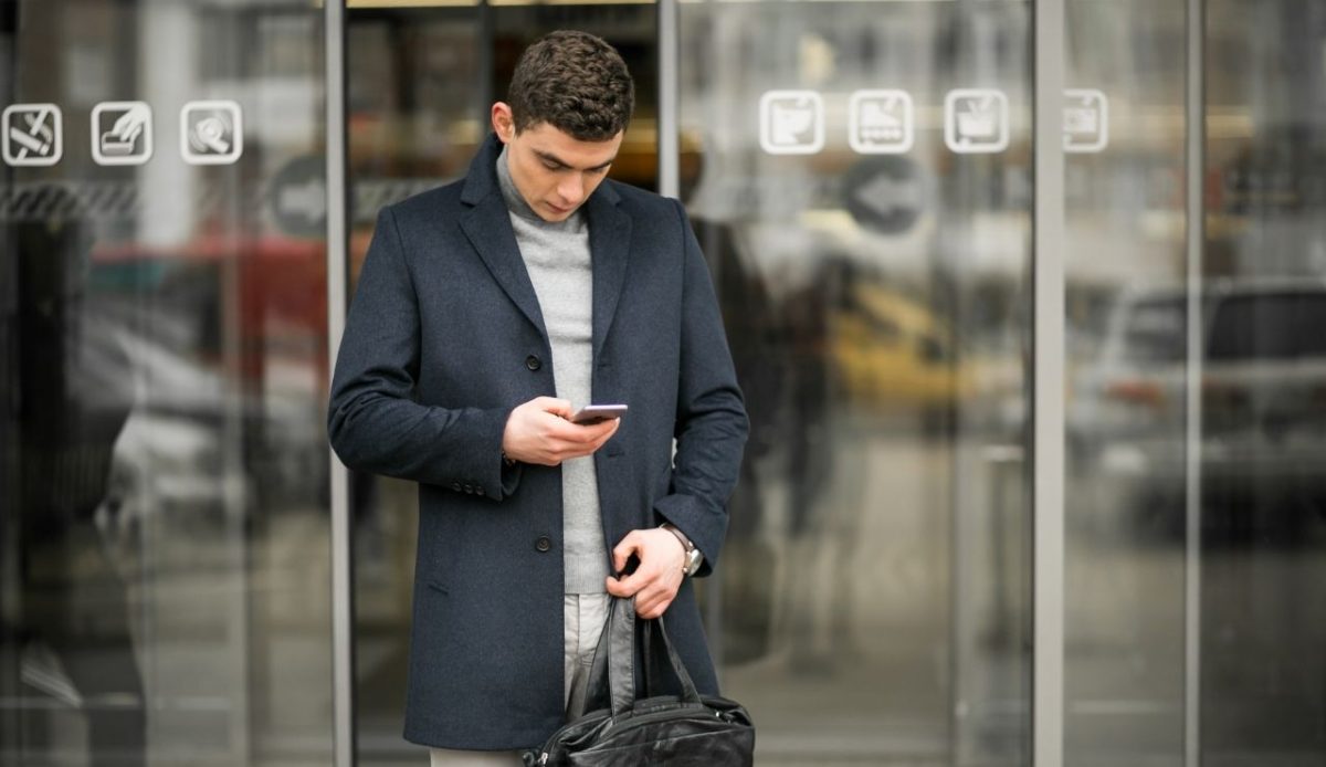 Man using mobile phone with bag outside                        
