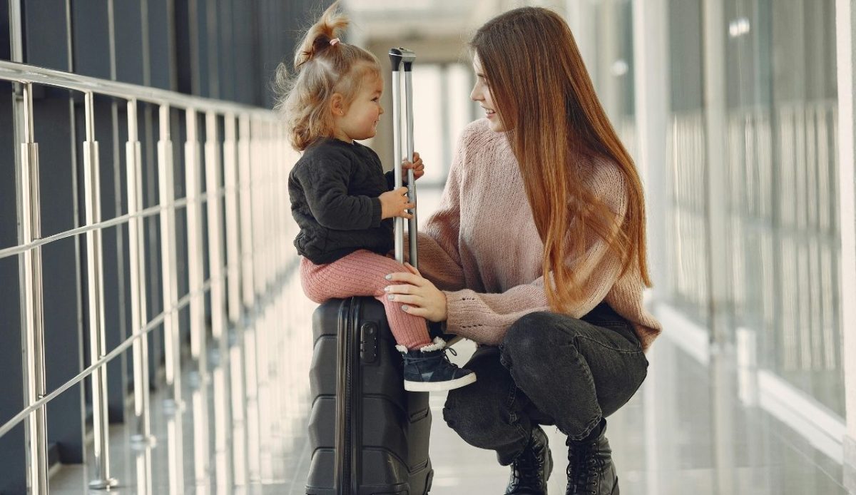 Smiling mother with daughter and suitcase in airport                         