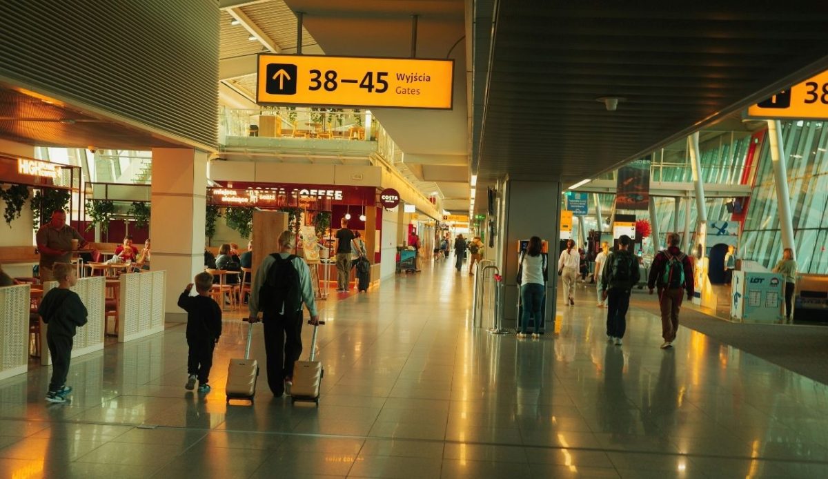 Travelers walking through Warsaw Chopin Airport terminal in Poland              