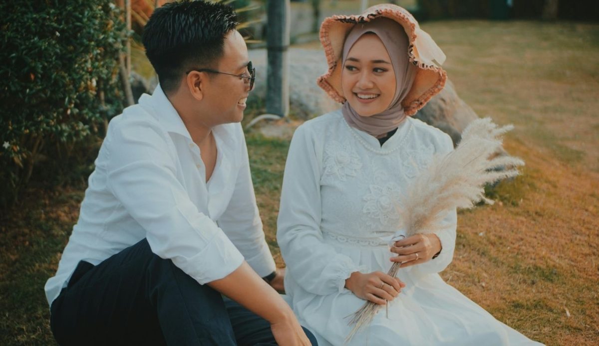 Woman Wearing White Long-sleeved Dress Holding White Flower Sitting Beside of Man Wearing White Dress Shirt and Black Pants                      
