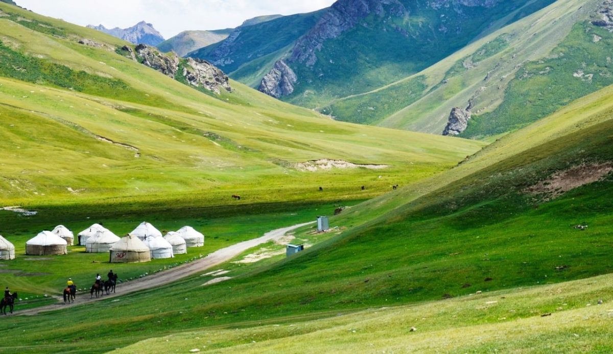 Yurt camp and riders in the green mountain valleys of Kyrgyzstan                     