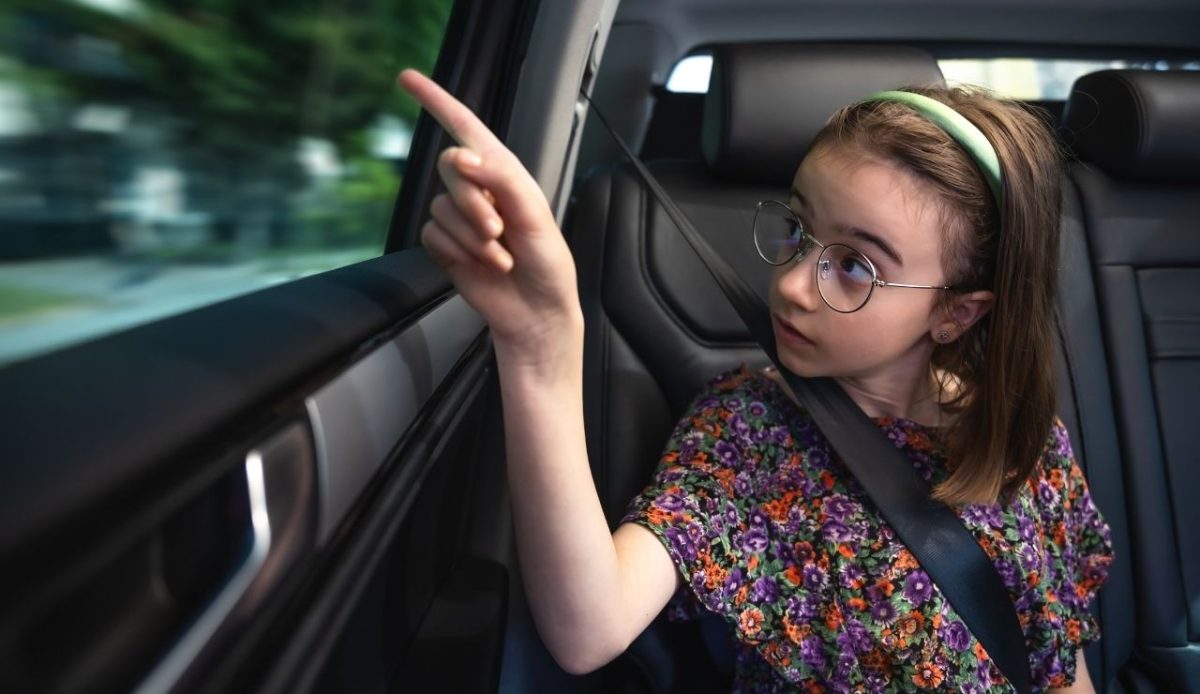 a girl is pointing out something from inside car          