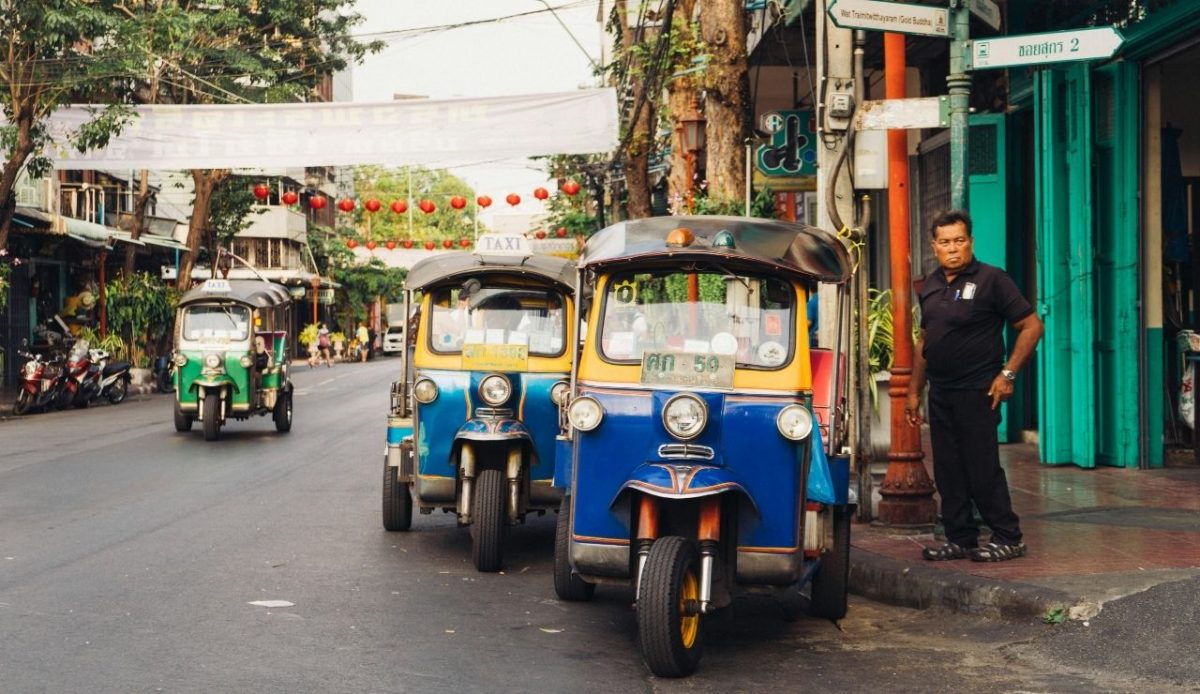 a man is standing near Tuk Tuk                  