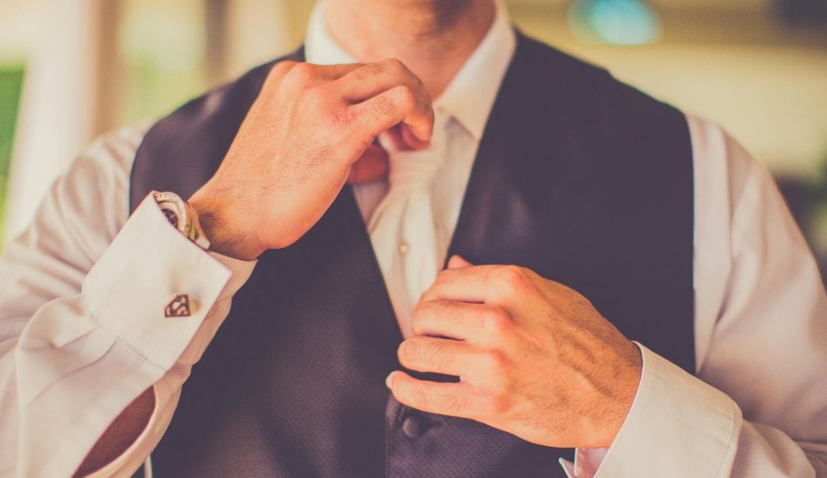 a person is setting a tie knot wearing formal dress