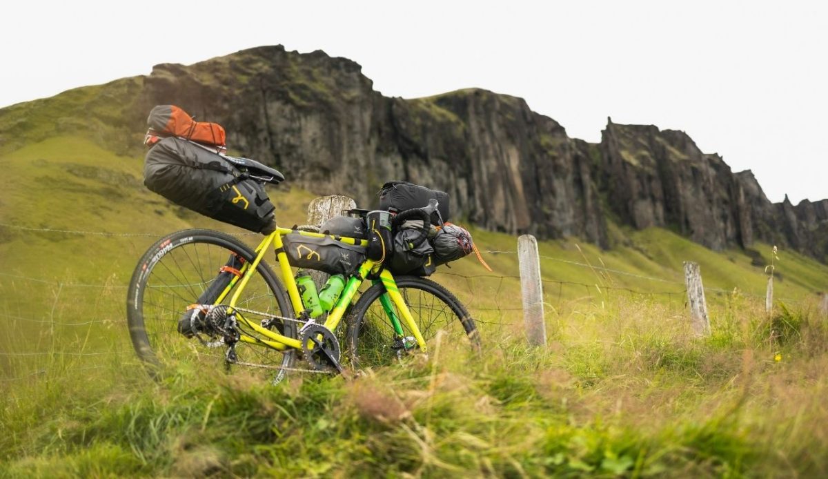 a yellow bike with a heavy backpack strapped to the back of it                       