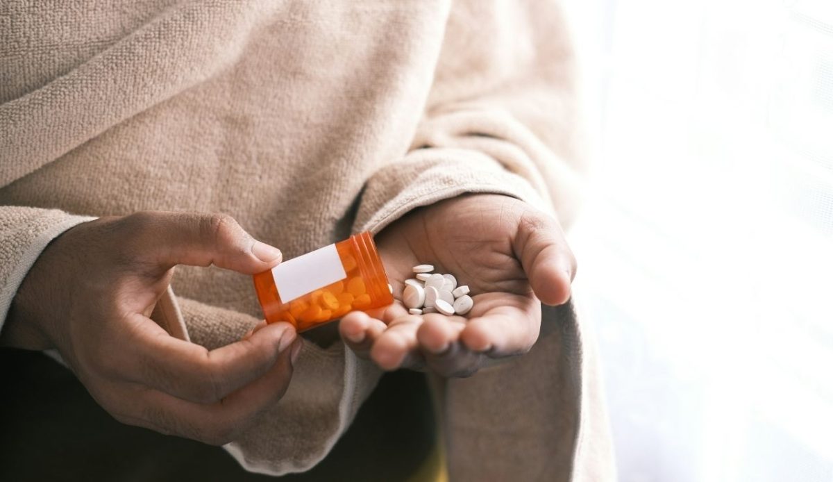man's hand with pills spilled out of the container