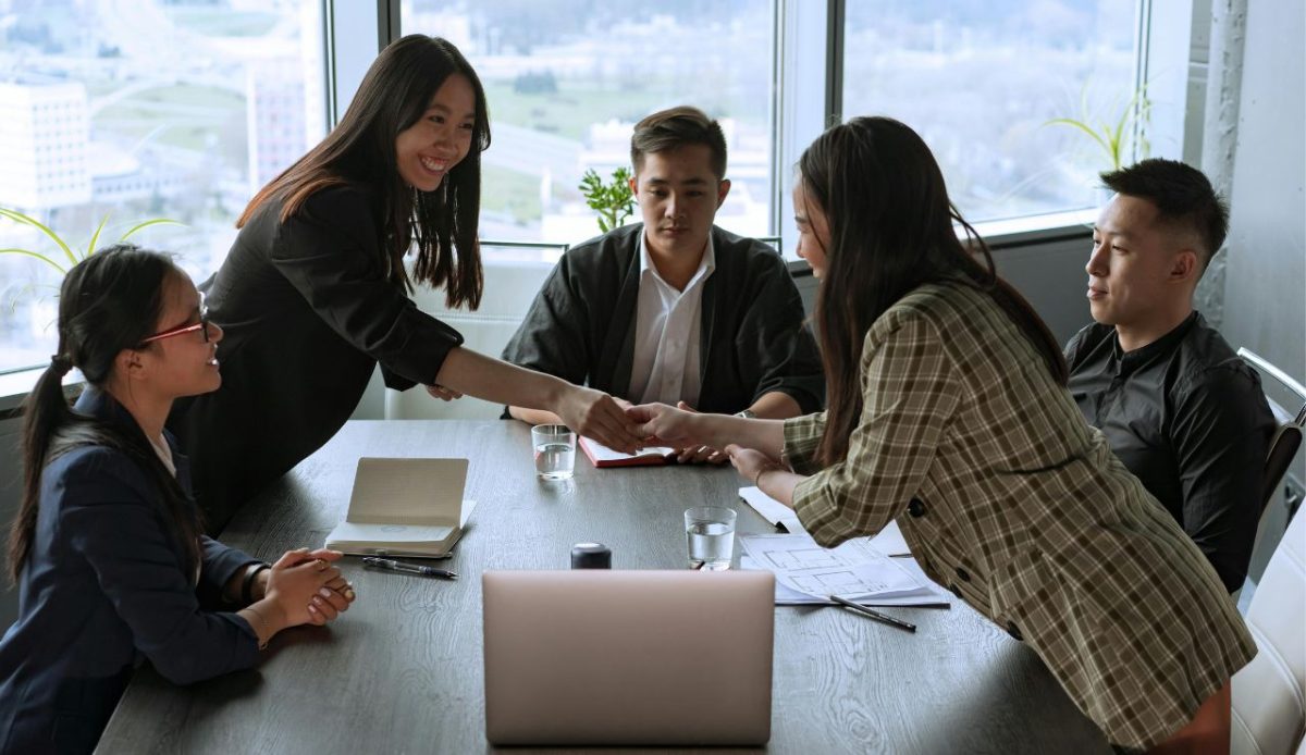 shake hand between two woman at group meeting       