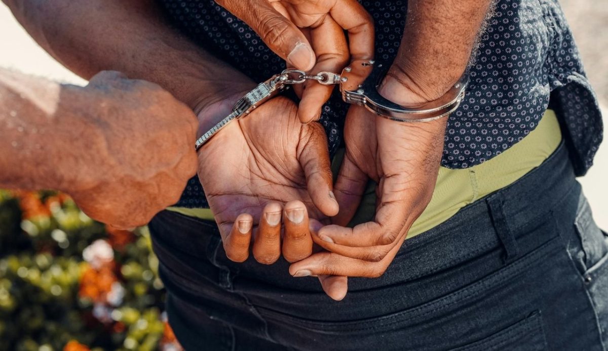 Person being handcuffed by police with hands behind their back outdoors                  