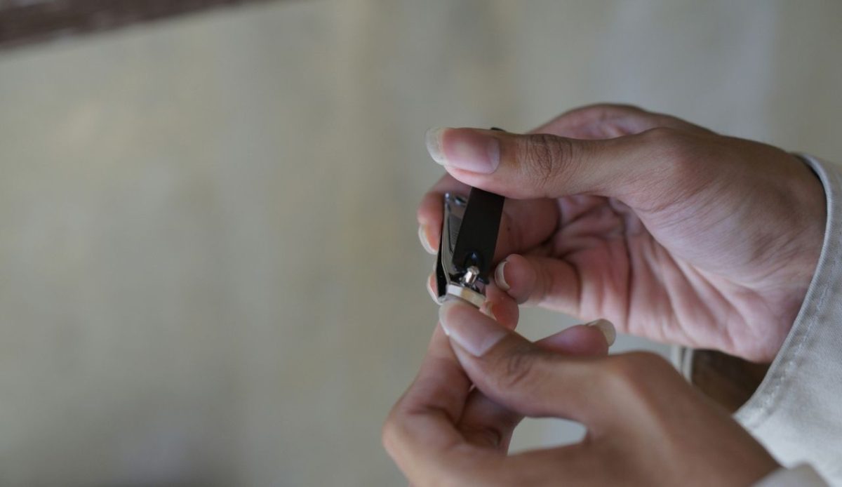 Close up of a person cutting his fingernail using nail clipper                     
