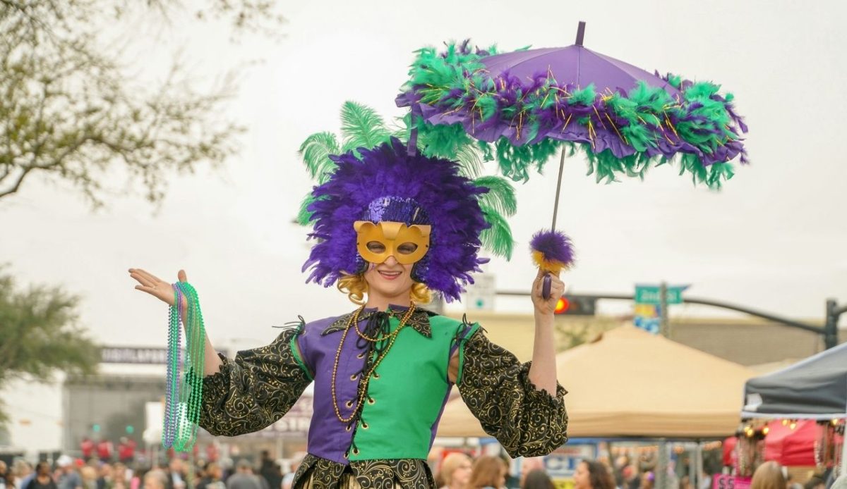 Lady dressed in full Mardi Gras outfit with decorated umbrella at a festival.                       