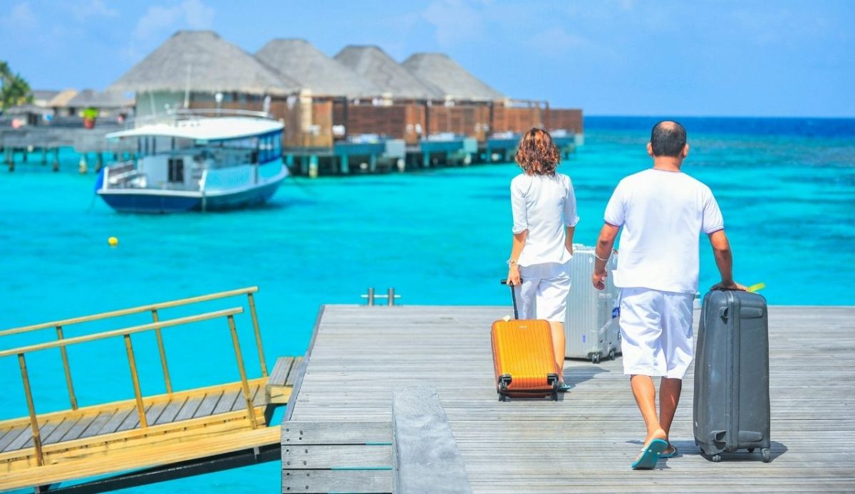 Man and Woman Walks on Dock leading to beach                                