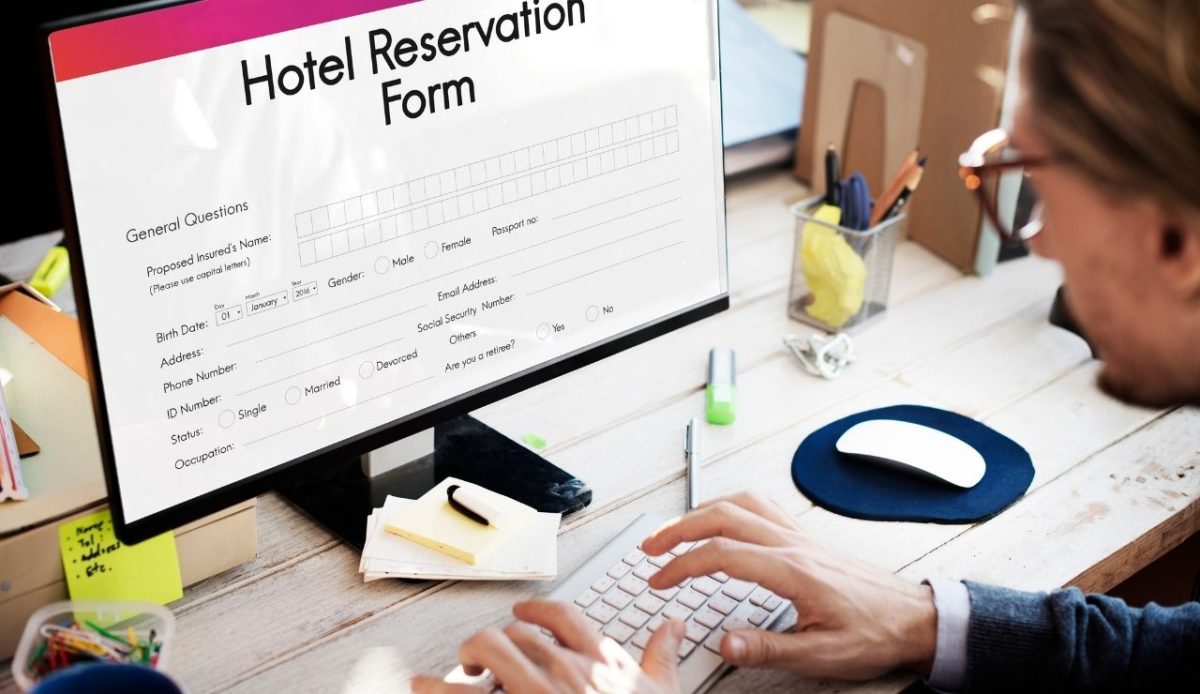 Person filling out an online hotel reservation form on a desktop computer 