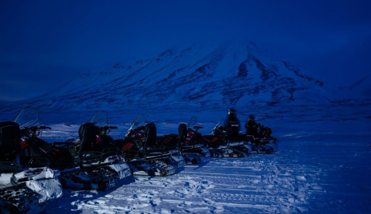 Snowmobiles on a safari with the mountains and fjords in the polar night.  Longyearbyen, Svalbard and Jan Mayen                           