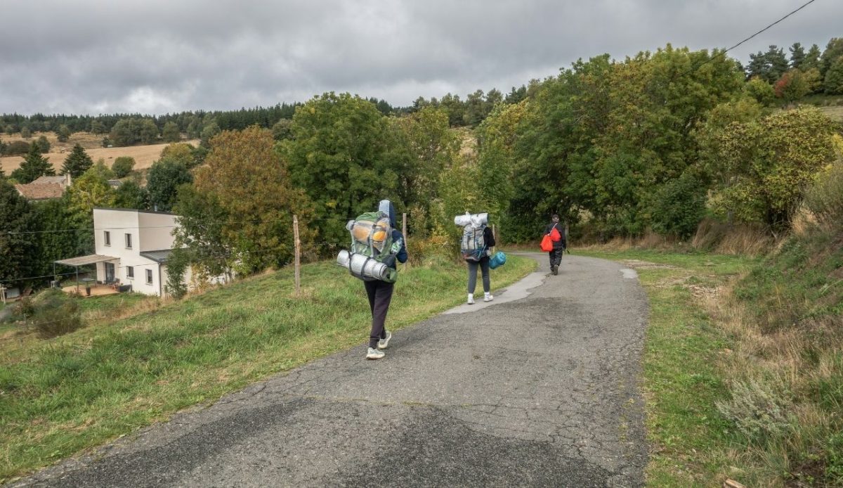 12 Seasonal Hiking Goals to Make 2026 Your Best Outdoor Year Yet 9 Three hikers bagpack walking through rural area
