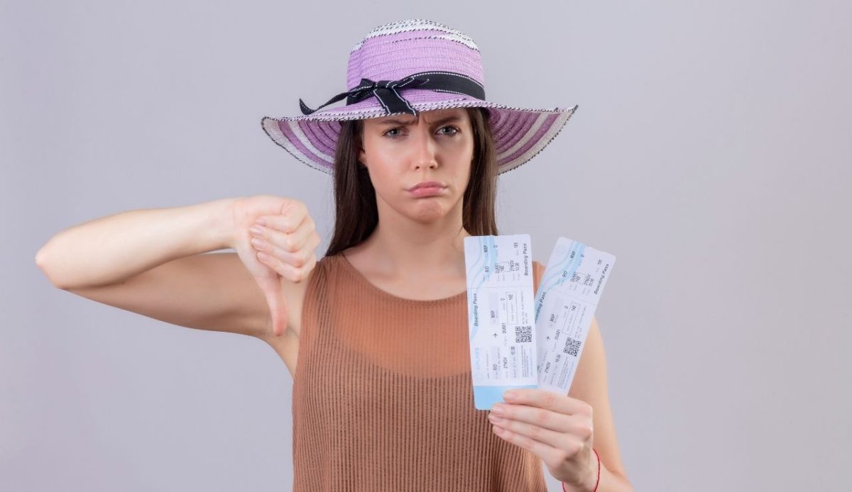 Young beautiful traveler woman in summer hat holding air tickets with frowning face showing disappointment over air ticket                                