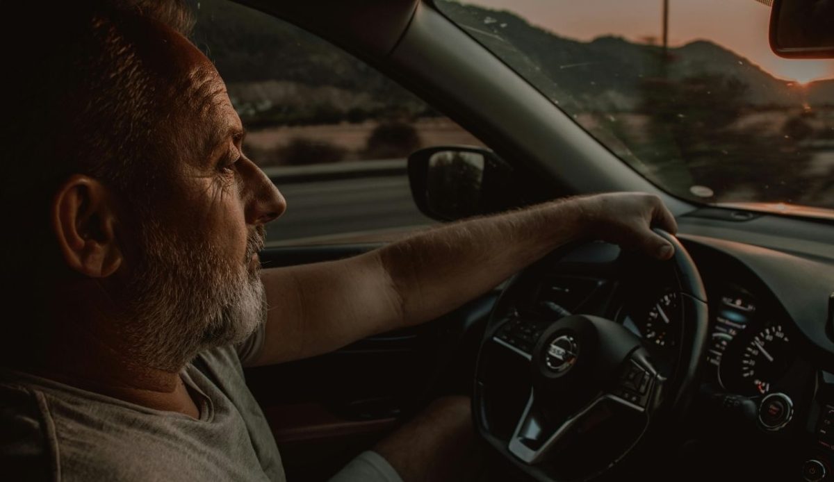 a man is driving car at evening time                             