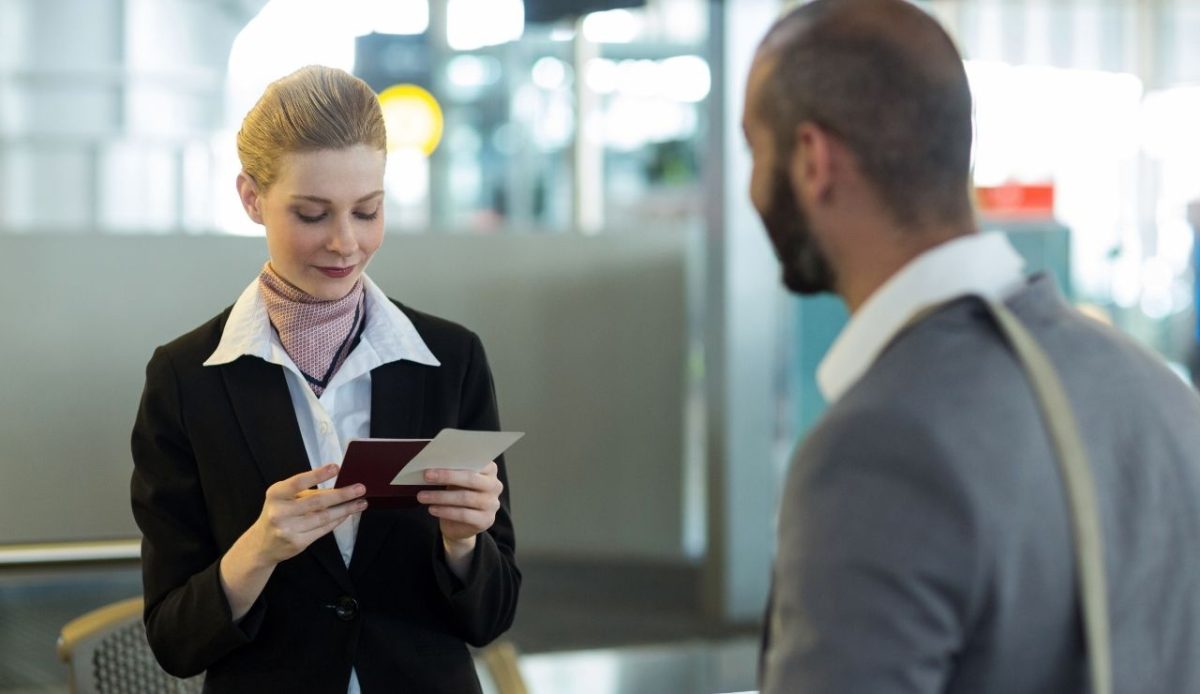 passenger standing at counter while attendant checking his passport                  