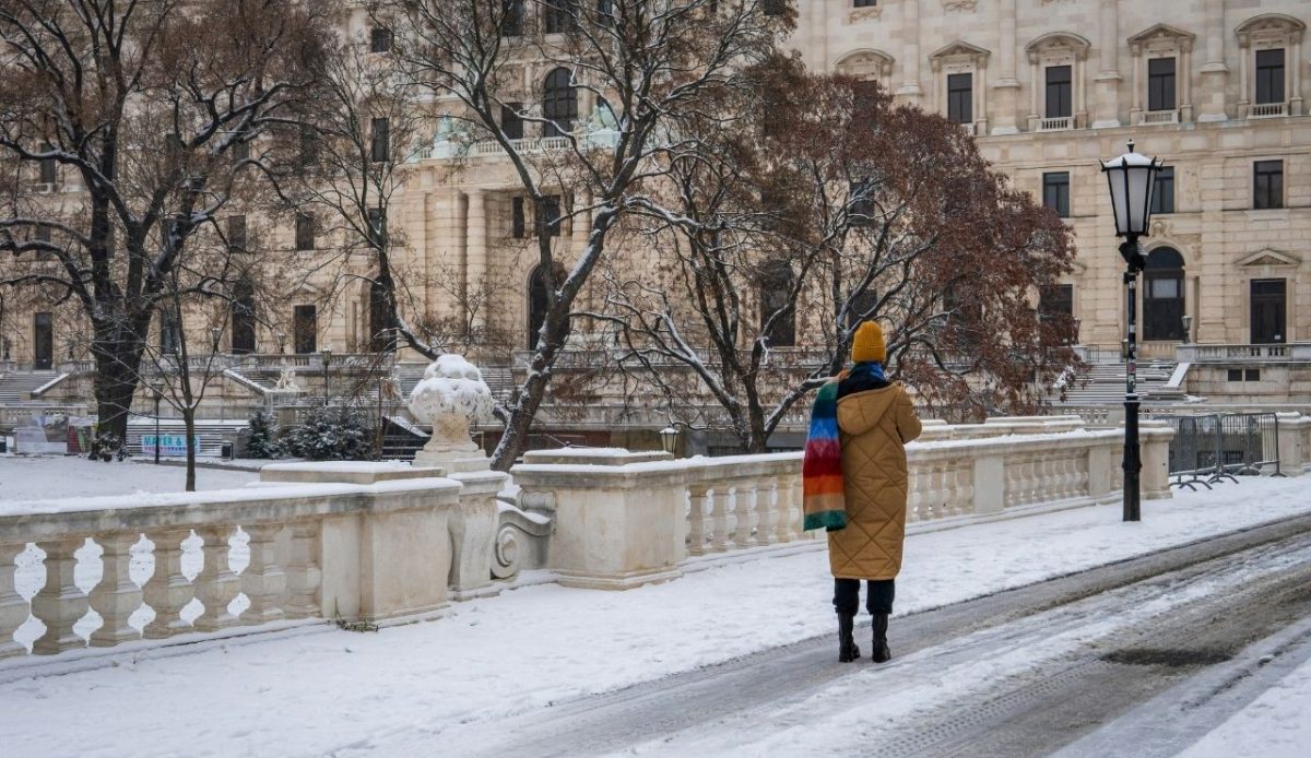 Person in snowy courtyard near historic building, Vienna Austria               