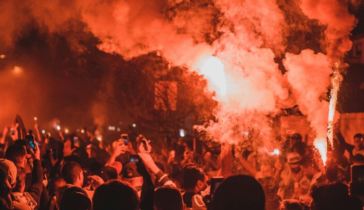 Anonymous people standing on street among smoke during protests at night at greece                            