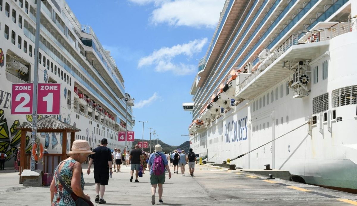 Cruise passengers walking between ships at port terminal 