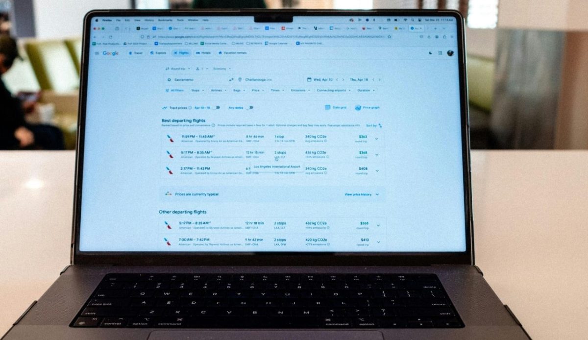 Laptop on table displaying flight search results, 
