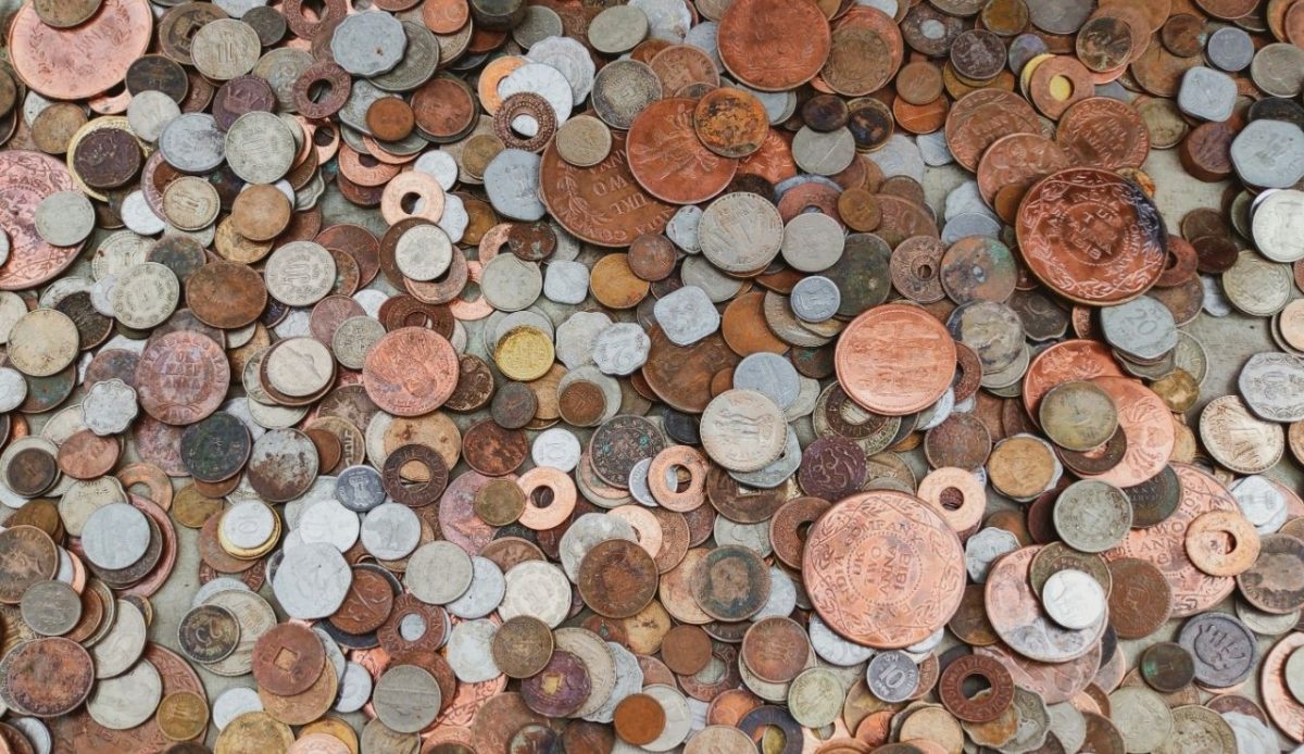 Pile of assorted old coins in mixed metals displayed together, representing antique or counterfeit coin sales to visitors                             