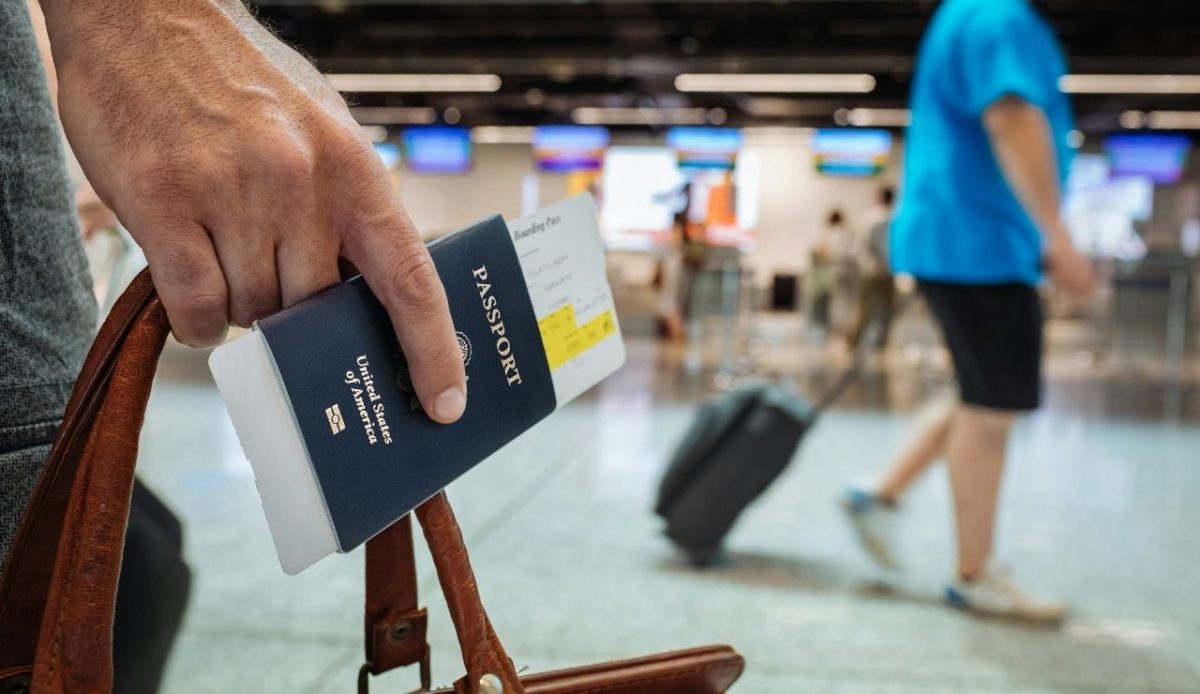 person holding American passport and suitcase at airport