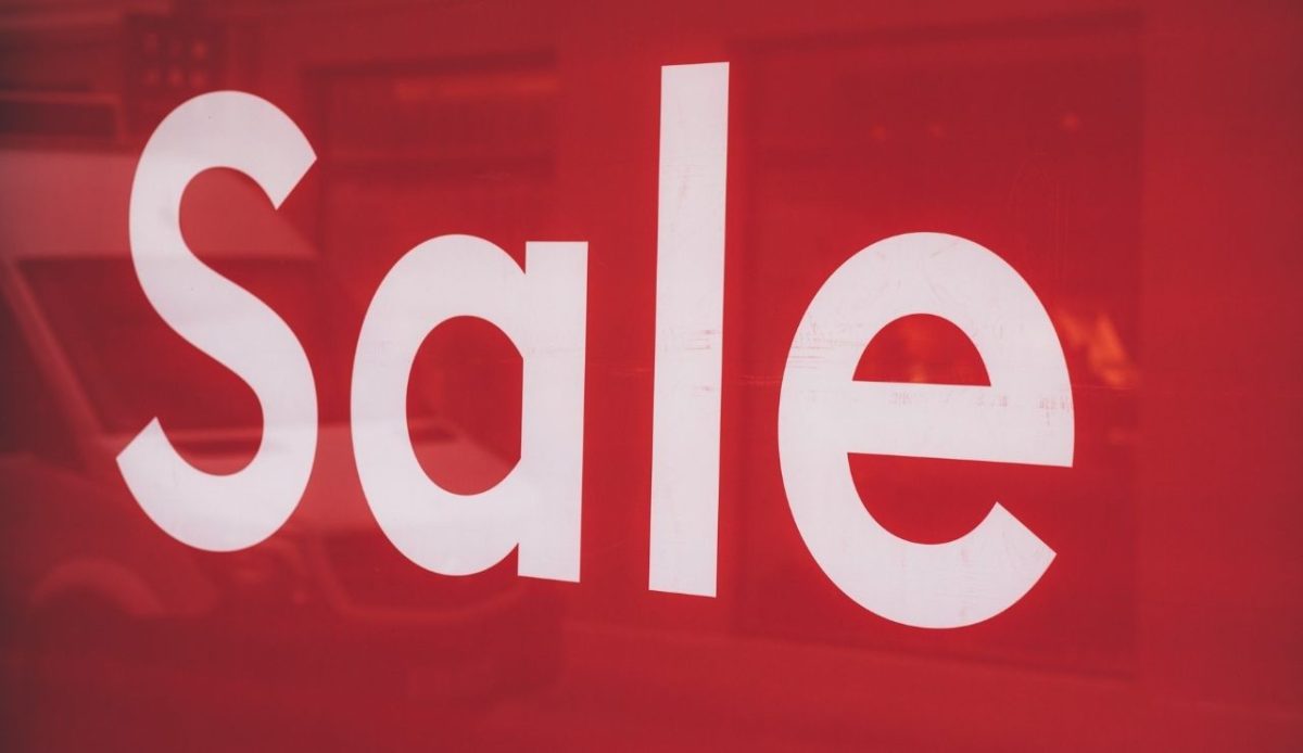 Red storefront sign with the word Sale in large white letters, representing counterfeit souvenir merchandise marketed to tourists                             