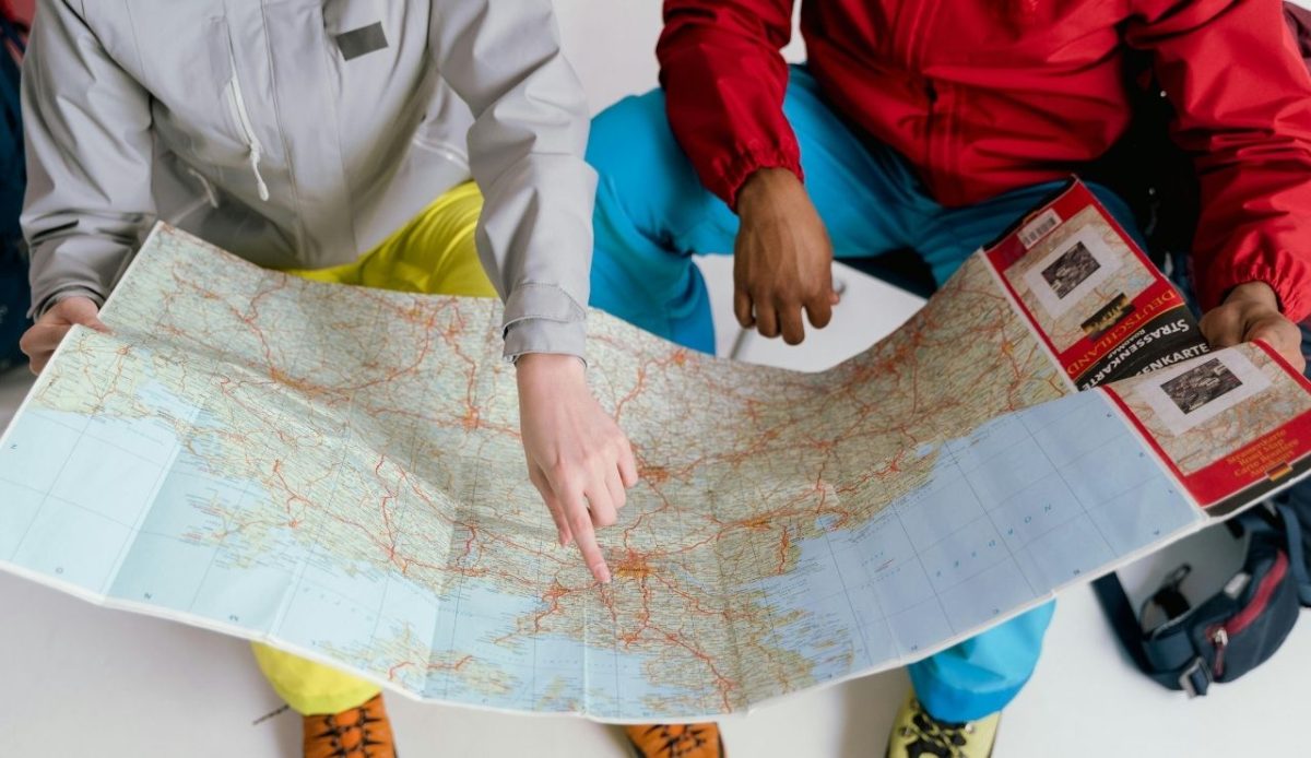 Two travelers planning a trip together while looking at a large world map