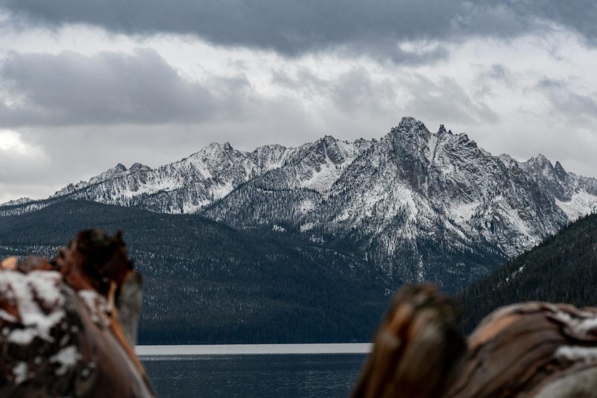 Breathtaking view of snow-capped Sawtooth Mountains over a serene lake in Lowman, Idaho.