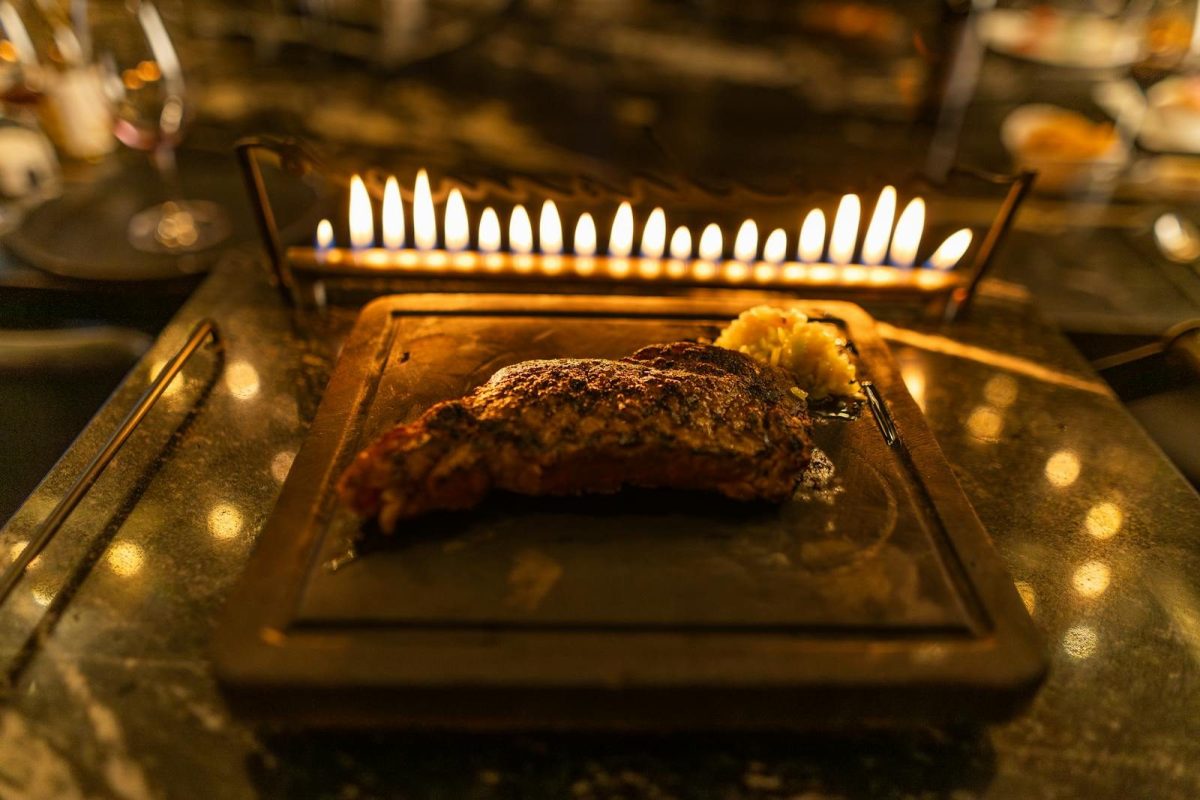Burnt gourmet steak served on a heated stone platter with ambient flames creating a cozy dining experience.