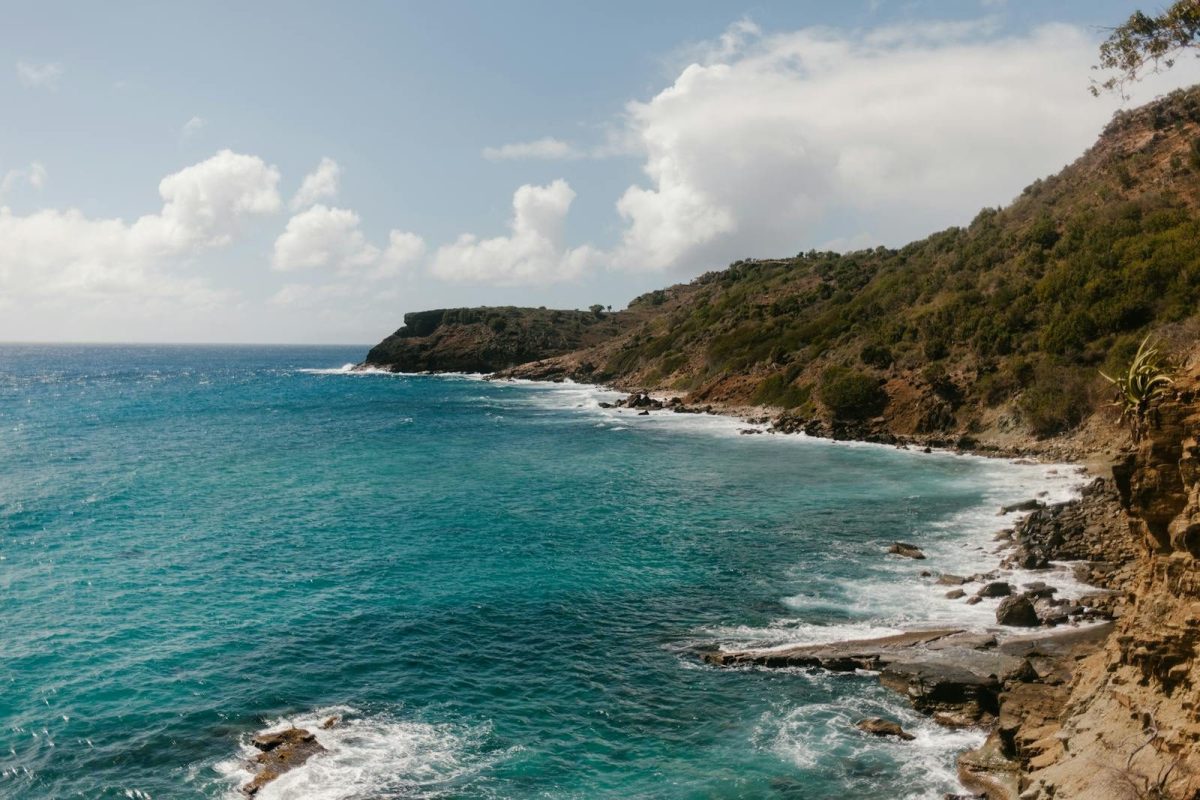 Breathtaking view of a rocky coastline with calm turquoise waters and a blue sky above.