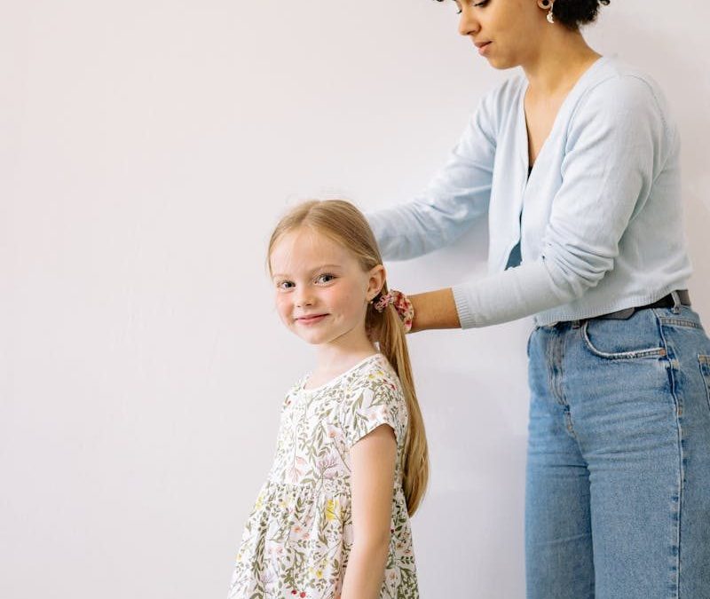A loving parent fixing her child's hair indoors, creating a joyful bonding moment.