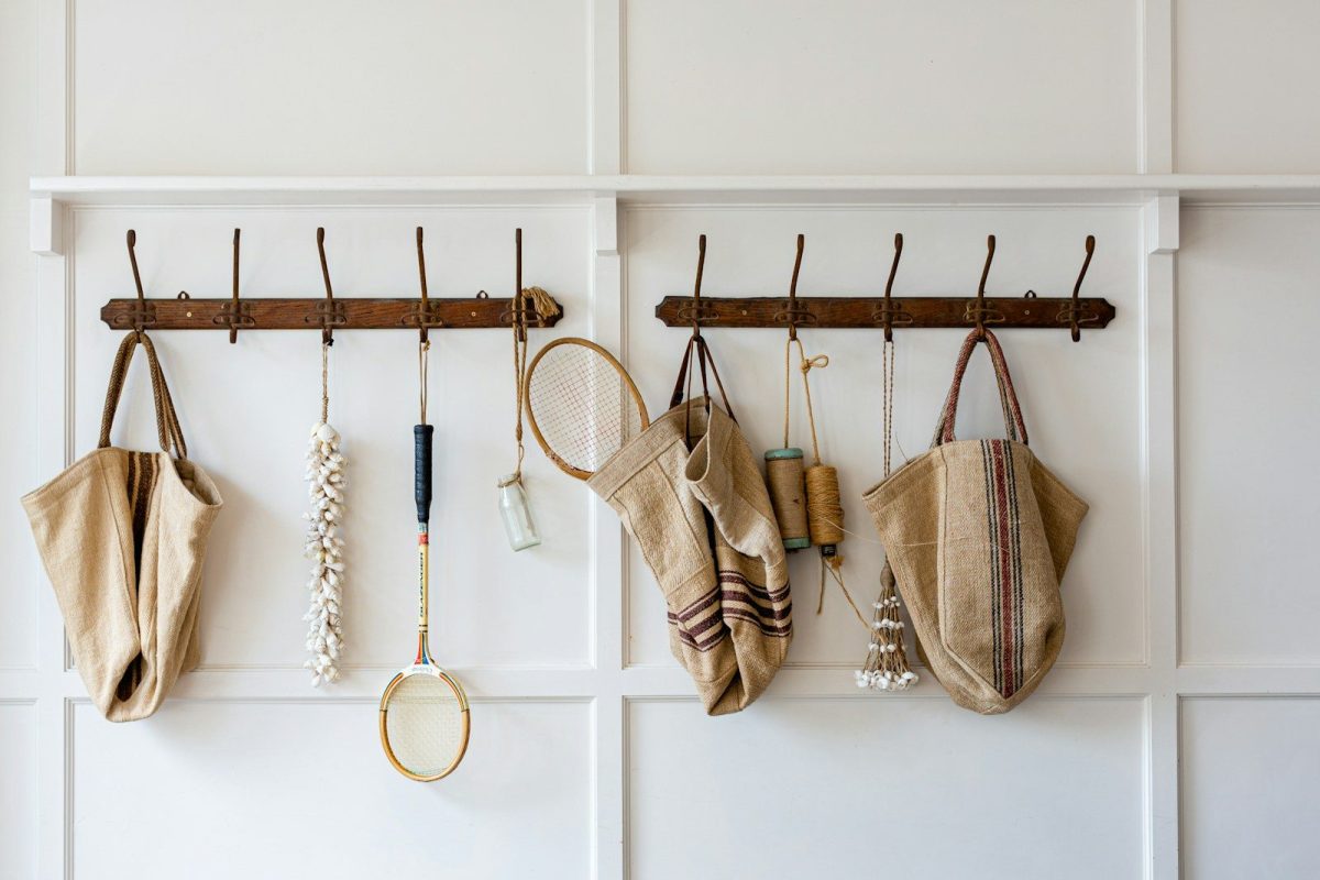 Brown and white sling bags hanged on white wooden wall