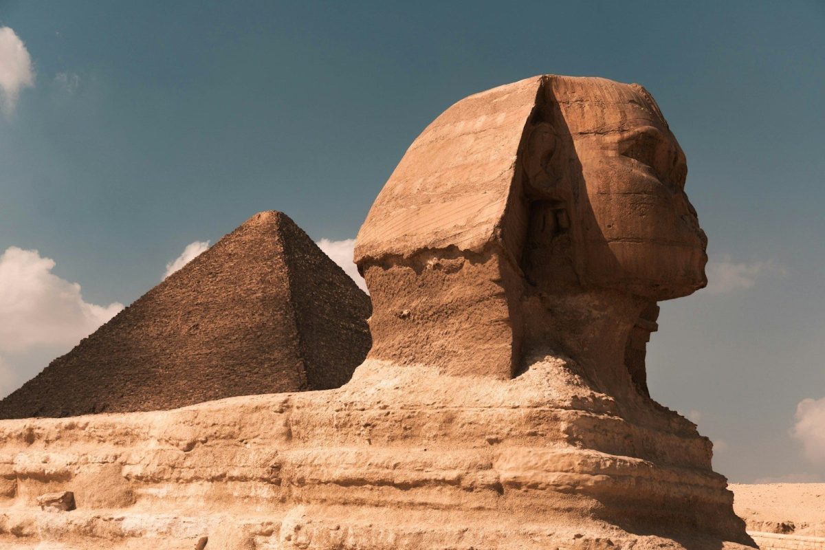 a large rock formation with Great Sphinx of Giza in the background