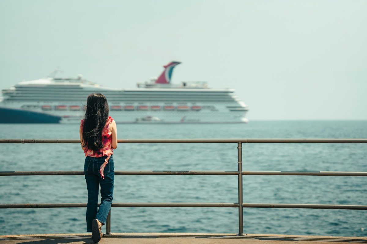 Woman watches a large cruise ship on the ocean.