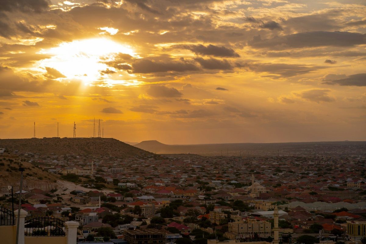 The sun is setting over a city and hills