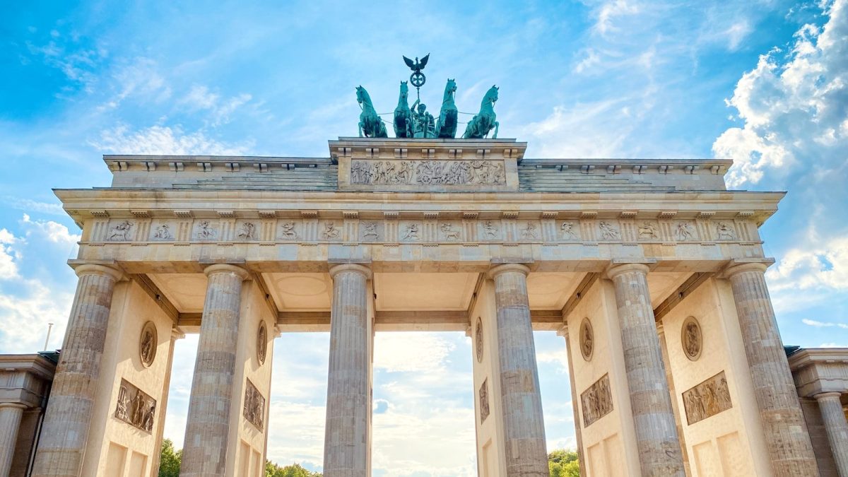 a large stone building with columns and statues on top with Brandenburg Gate in the background