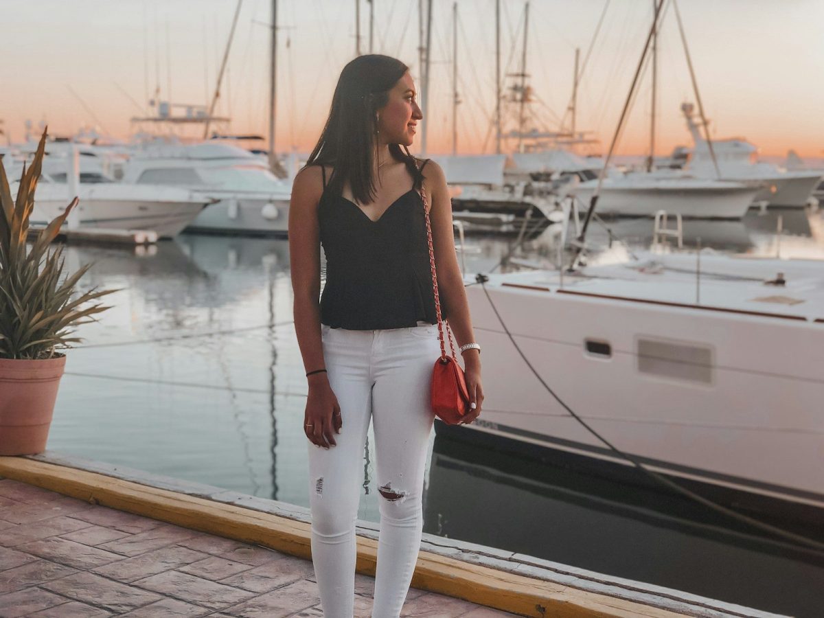 woman in black tank top and white pants standing on dock during daytime